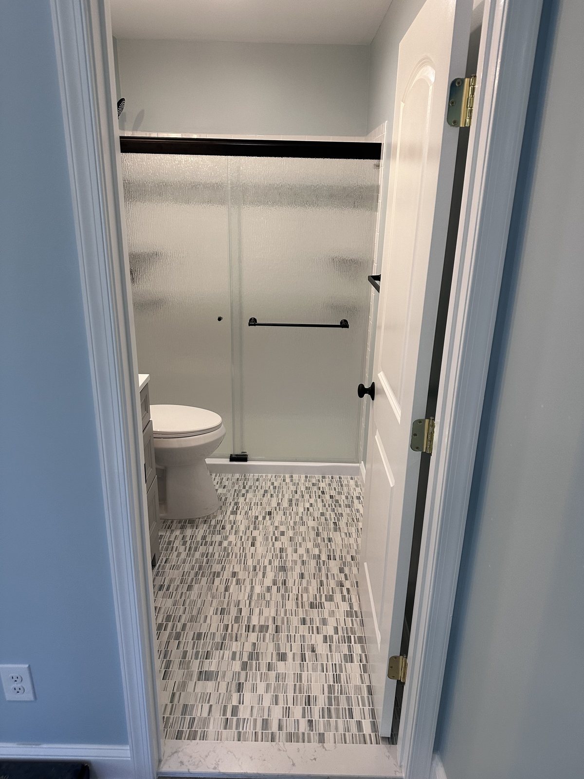 Hall bath with mosaic floor and a frosted sliding shower door
