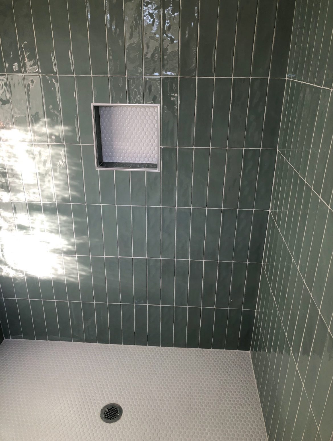 Glossy green subway-tile shower with a penny-round niche and floor