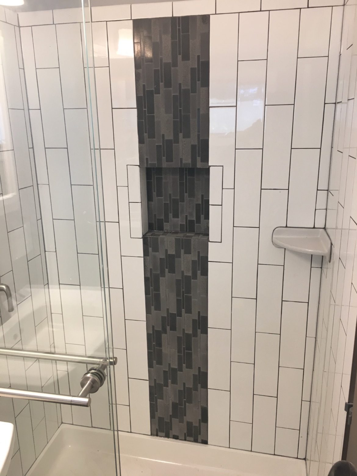 White subway shower with a vertical mosaic strip and glass door