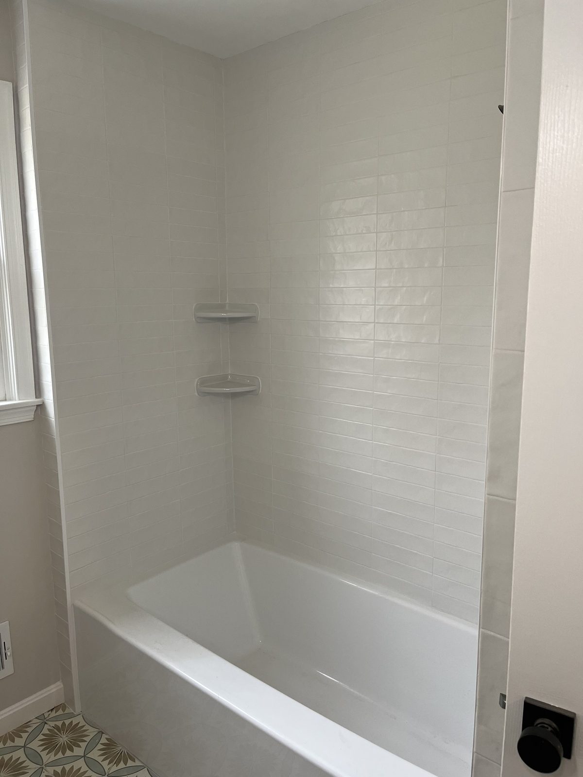 White subway-tiled tub surround with corner shelves