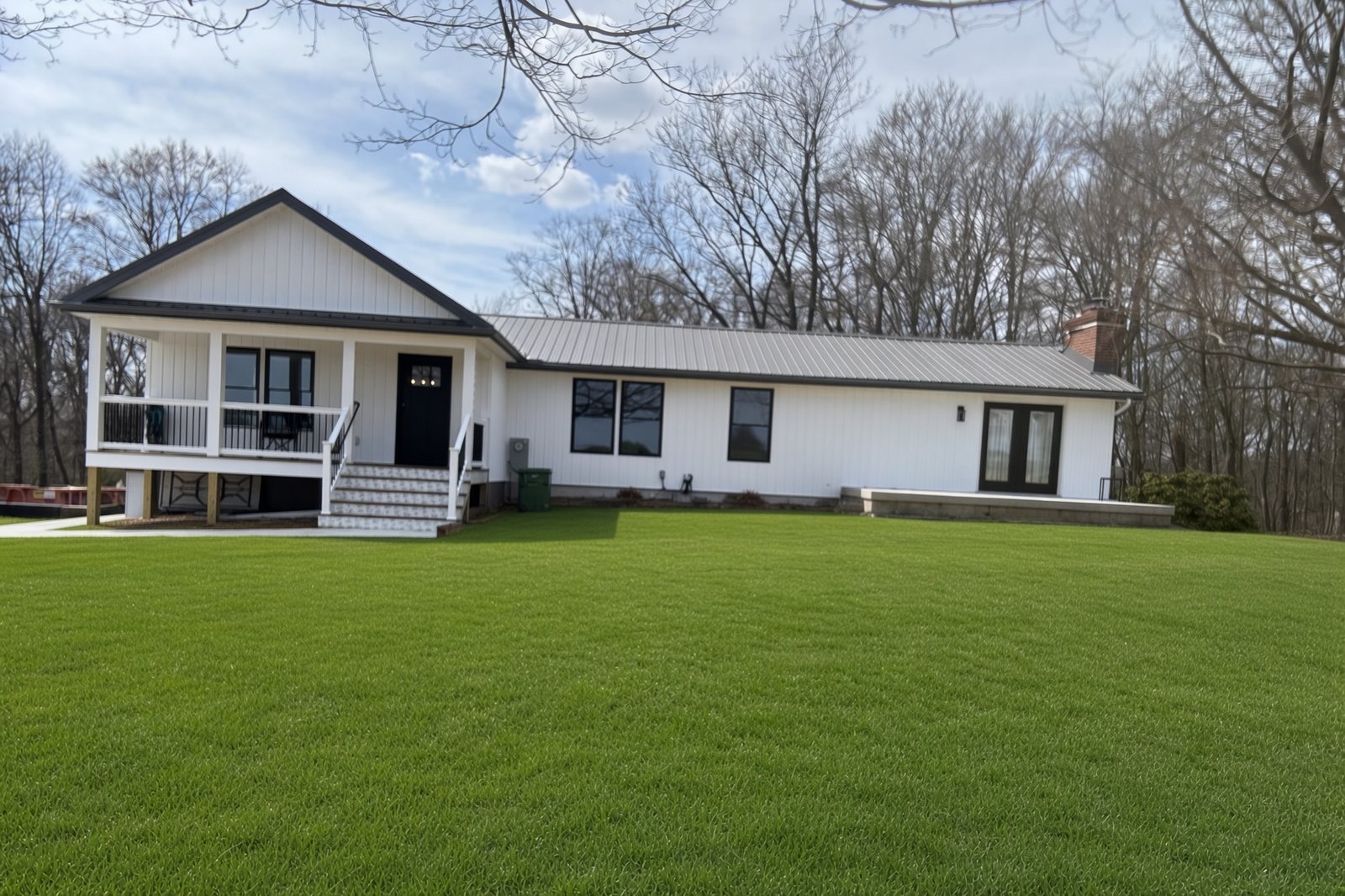 Finished white farmhouse addition seen from the yard in spring