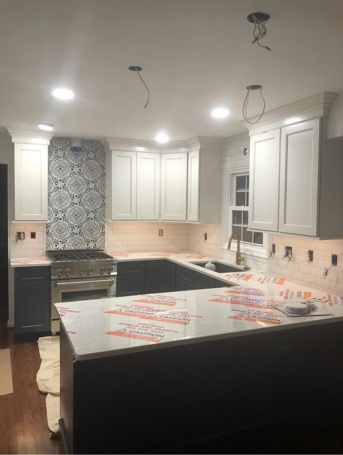 Same navy and white kitchen during stone and lighting install
