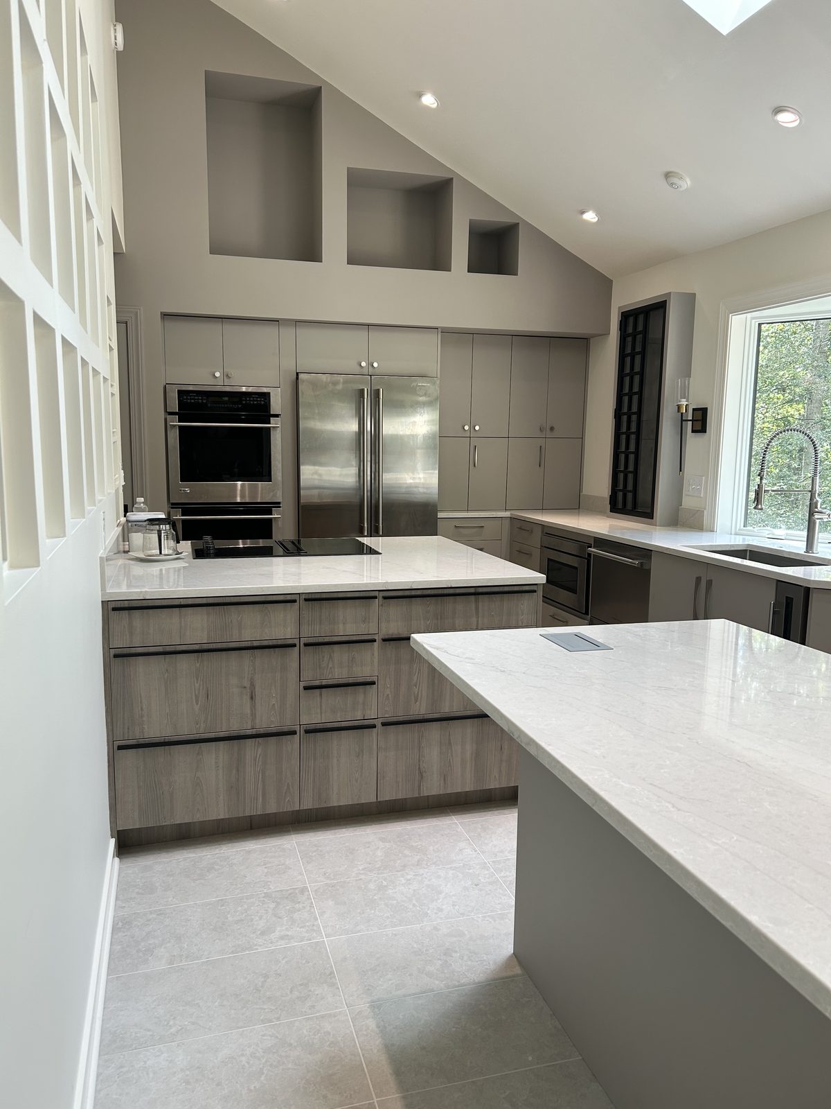Gray kitchen with a vaulted ceiling, stainless appliances, and a window over the sink