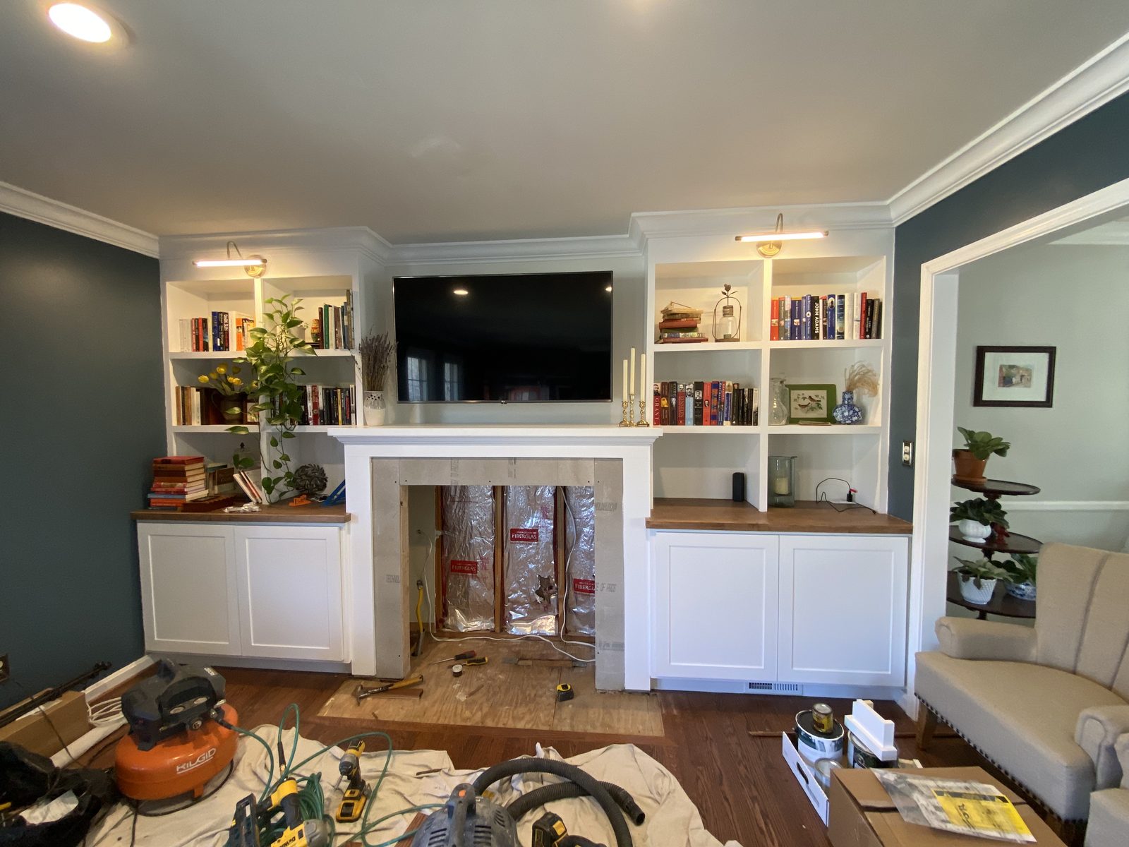 Painted built-in bookcases and cabinets flanking a fireplace, with picture lights