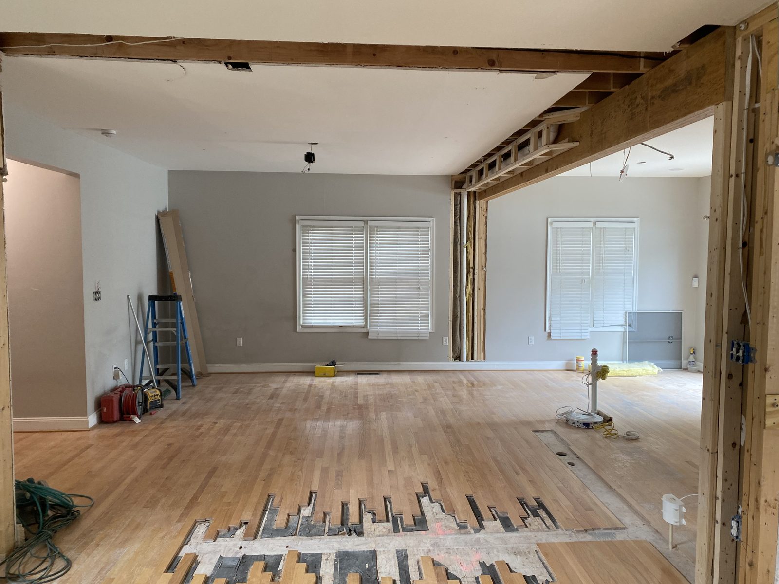 Interior wall opened up with a new beam and hardwood floor being patched