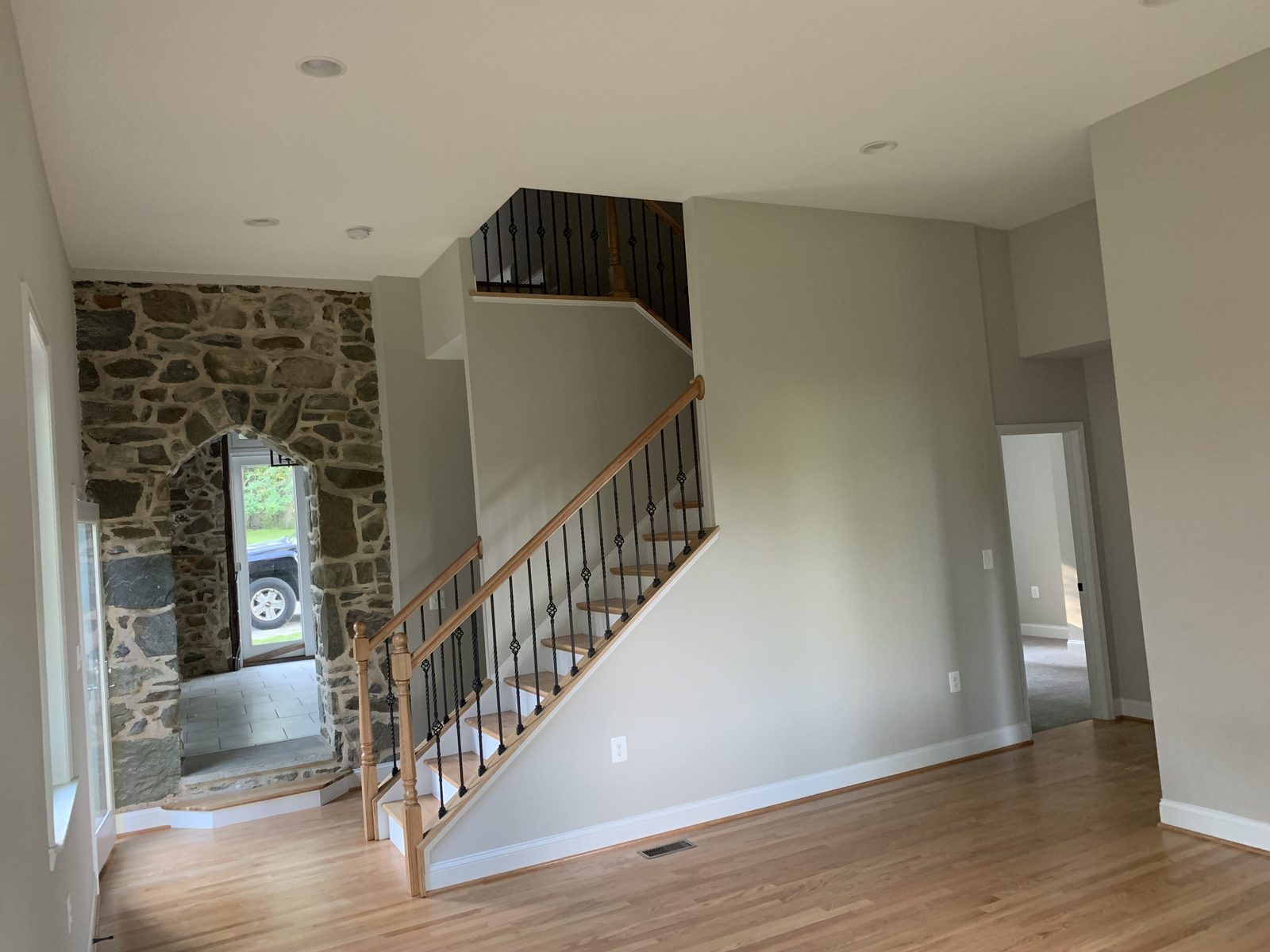 Open stair with wood treads, iron balusters, and an original stone arch