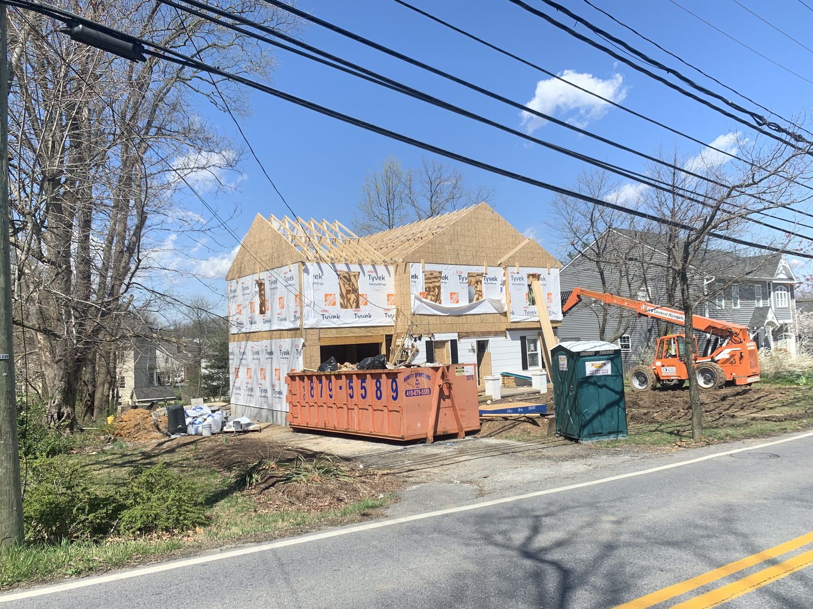 Two-story addition in framing and housewrap on a residential street