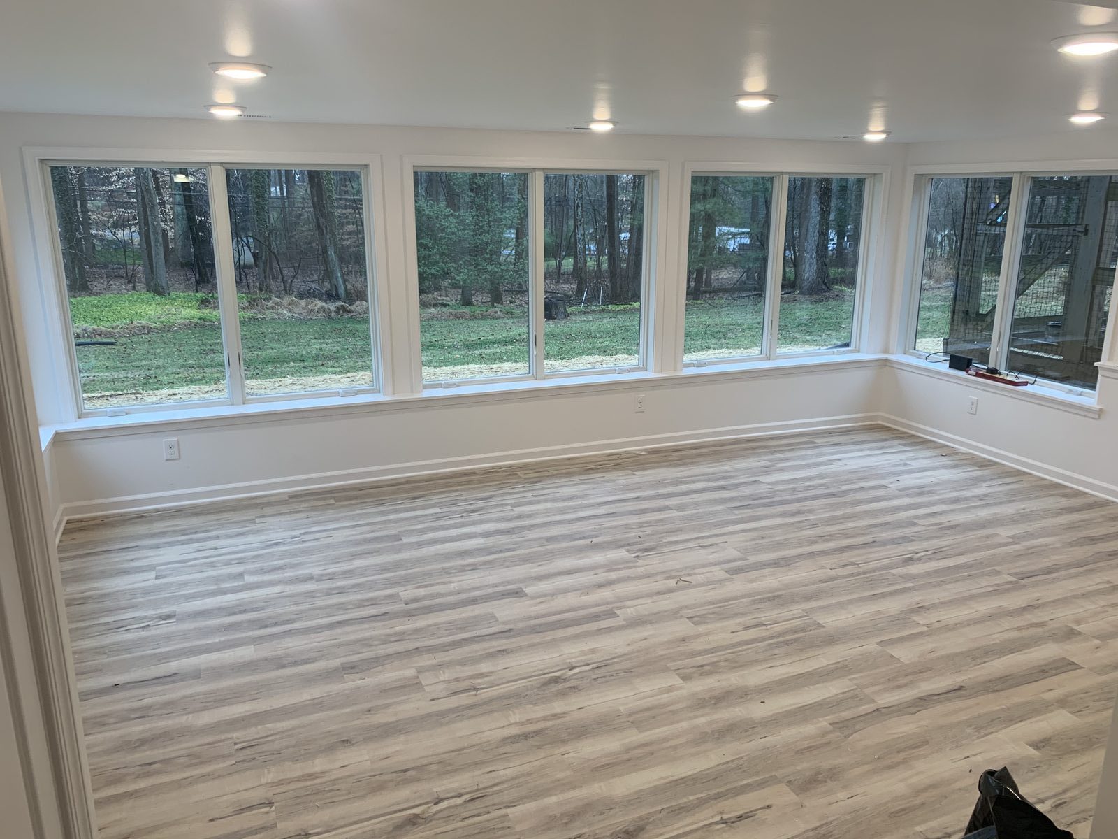 Finished sunroom interior with a wall of windows looking into the woods