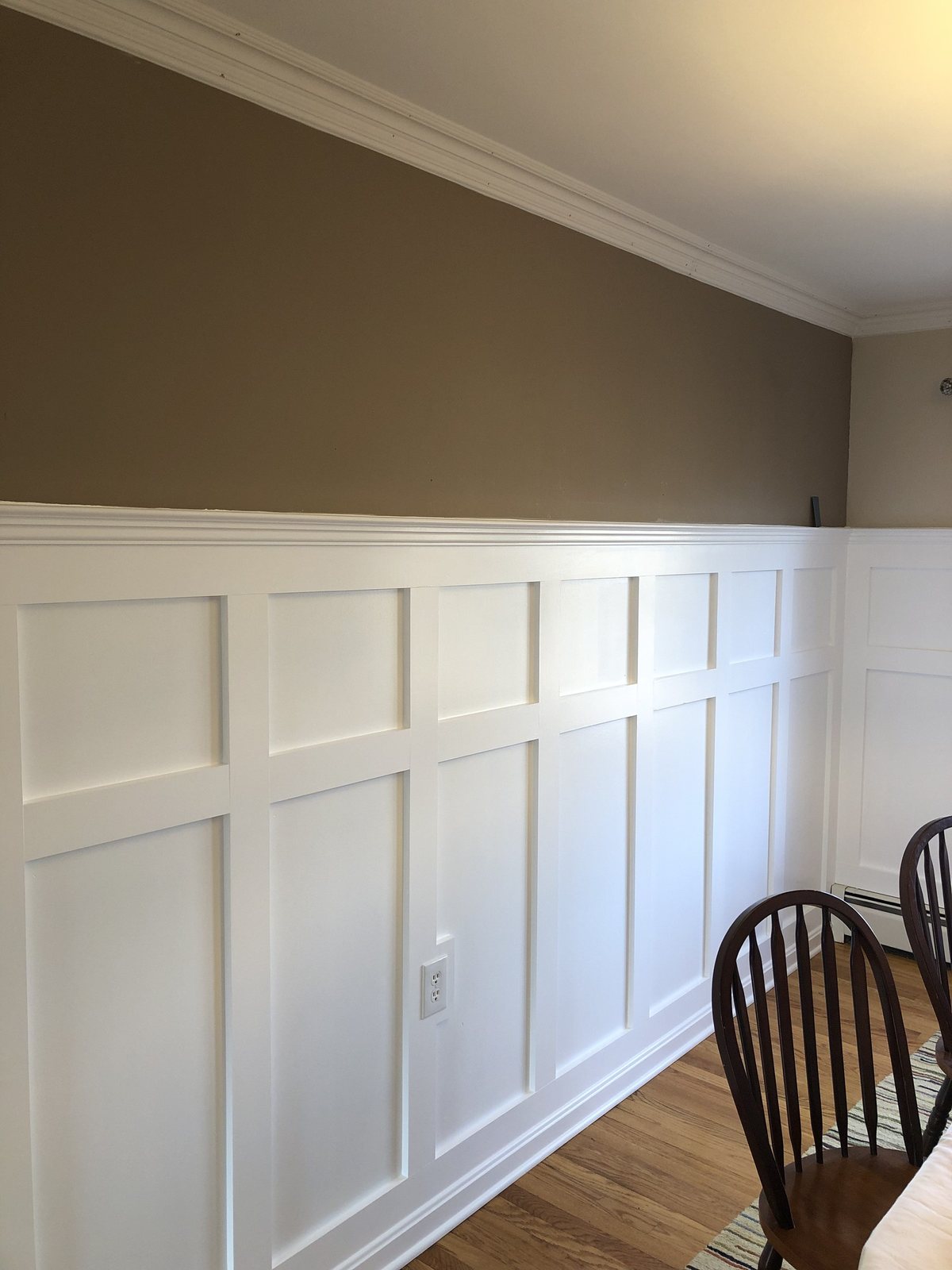 White box-panel wainscoting and crown in a dining room with hardwood floors
