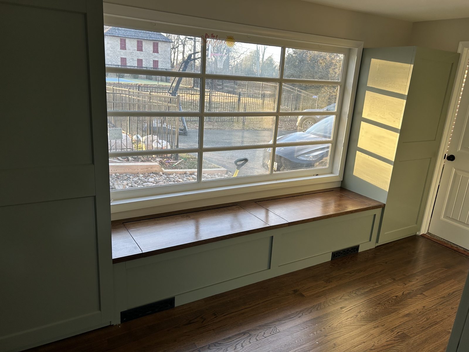 Window seat with a wood lid and painted millwork under a grid window